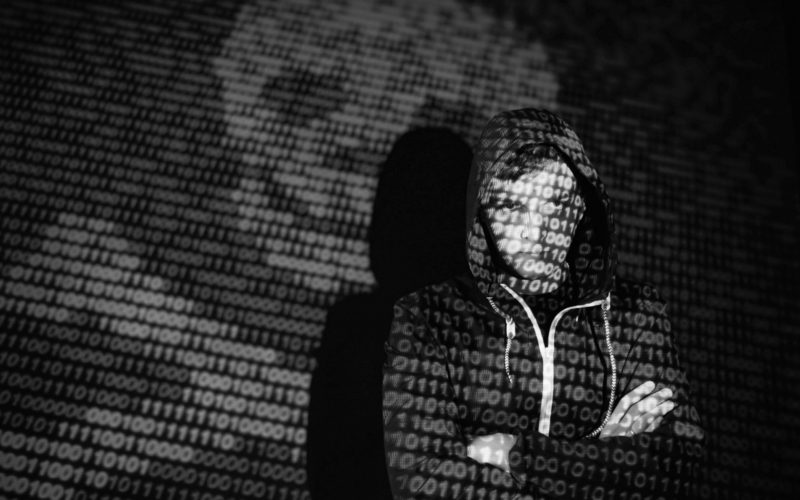 cyber attack with unrecognizable hooded hacker using virtual reality digital glitch effect